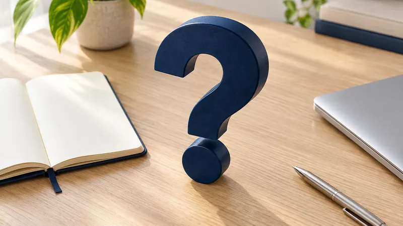 A question mark on a desk beside an open notebook